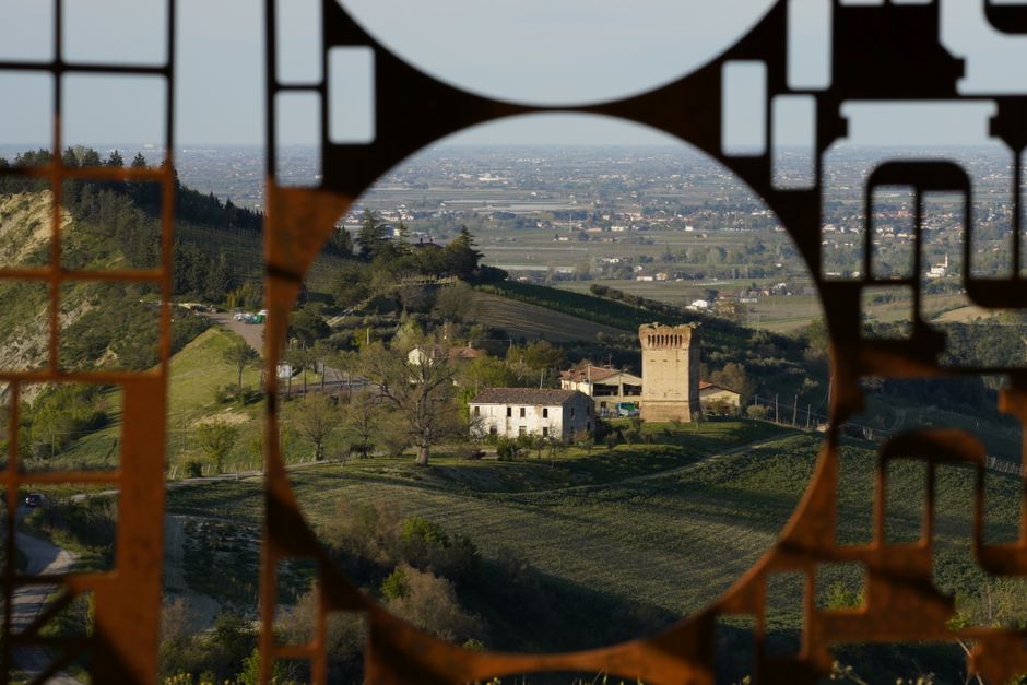 Explore a scenic countryside landscape through an intricately designed metal frame, capturing hills and a tower.