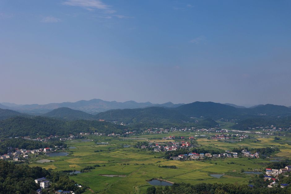 Breathtaking aerial view of countryside town surrounded by green fields and hills under a clear sky.